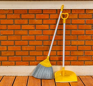 Broom and dustpan lean against a red brick wall - legislative update